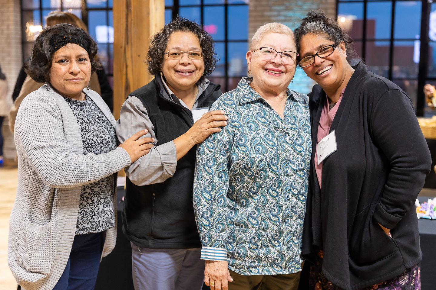 Four Latinas standing together and smiling at the camera at a Somos Comunidad Fund launch party.